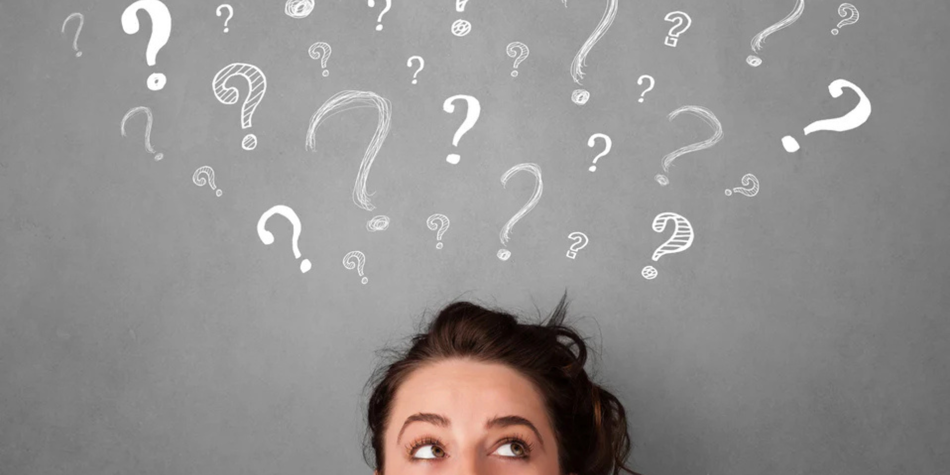Woman looking upward at chalk-style question marks floating above her head