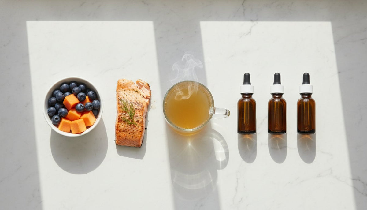 Salmon, blueberries, papaya, steaming broth, and dropper bottles arranged on a sunlit marble surface