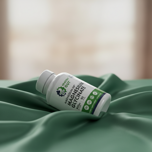 Tilted bottle of Magnesium-HP showing Healthy Gut label for magnesium glycinate on a green satin backdrop