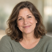 Smiling woman with shoulder-length brown hair in a green sweater, shown for a customer testimonial