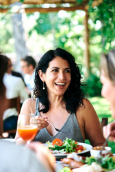 Middle aged woman enjoying a meal with friends on an outdoor patio