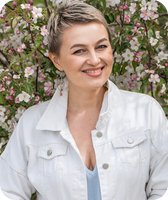 Smiling short-haired woman in a white jacket among pink and white flowering branches